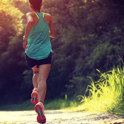 Runner athlete running on forest trail.