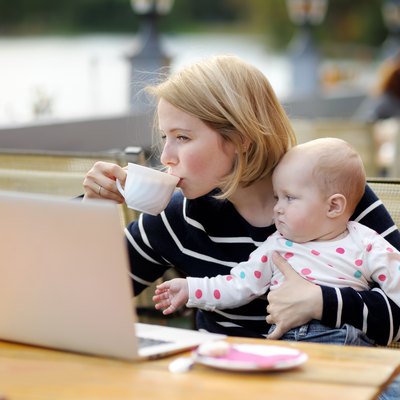 Young mother with her baby working or studying on laptop