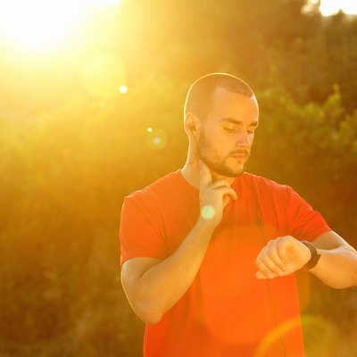 Sports man checking pulse and looking at watch
