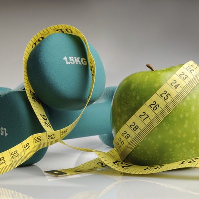 healthy apple, measuring tape and dumbbells
