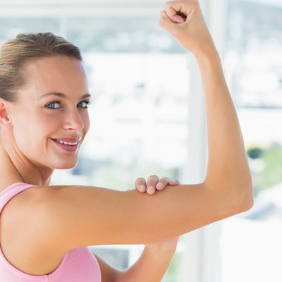 Young woman flexing muscles in gym