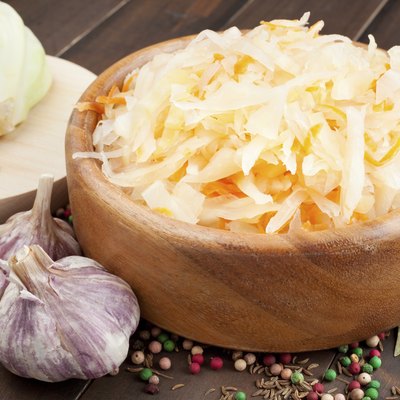 Sauerkraut with carrot in wooden bowl, garlic, spices and cabbage