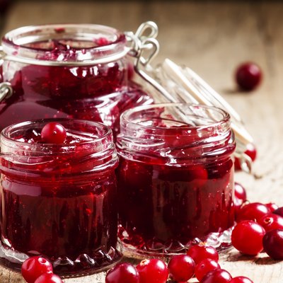 Delicious cranberry jam in glass jars and fresh cranberry