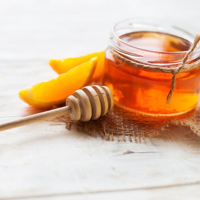 jar of honey and orange on wooden Table