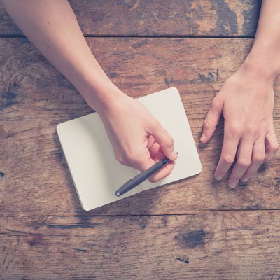 Woman writing in notepad at wooden table