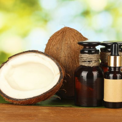 coconut oil in bottles with coconuts on green background