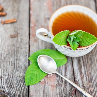 Cup of tea with mint on old wooden table