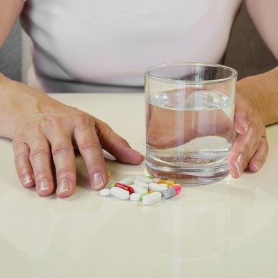 hand with pill and glass of water