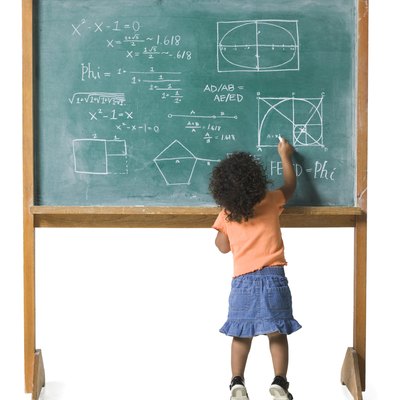 conceptual shot of a young female child as she works out a problem on a chalkboard