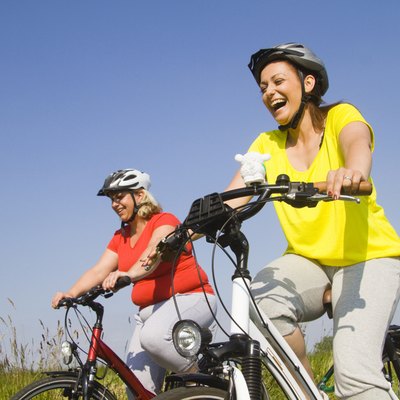 Two friends riding bicycles through field