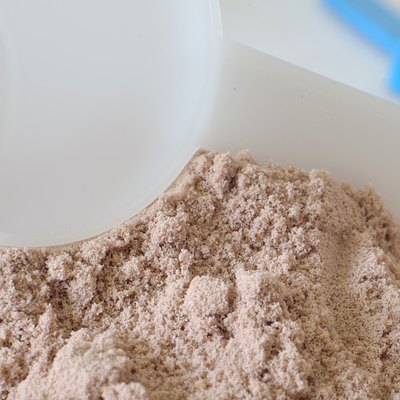 White scoop in heap of chocolate protein powder