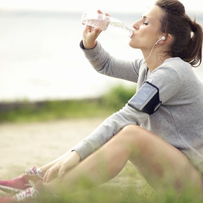Female Jogger Resting and Drinking Bottled Water