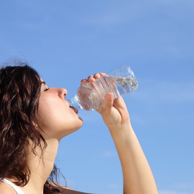 Profile of a woman drinking water from plastic bottle