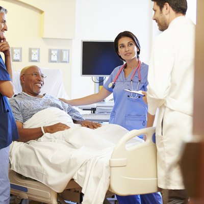 Medical Team Meeting With Senior Man In Hospital Room