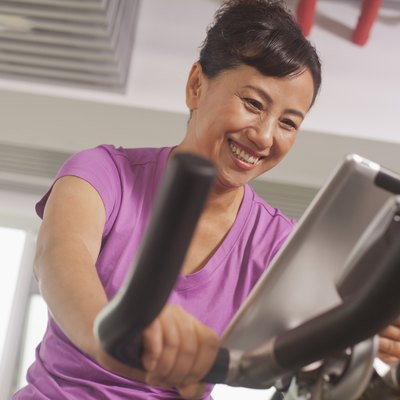 Woman smiling and exercising on the exercise bike with her trainer