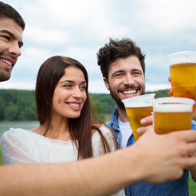 Group of friends toasting with beer in plastic glasses