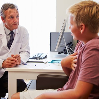 Teenage Boy Having Consultation With Doctor In Office