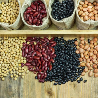 Different kinds of beans scattered on wooden background