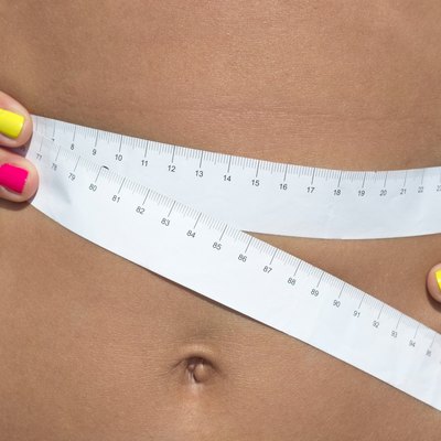 Girl measuring her waist at the seaside