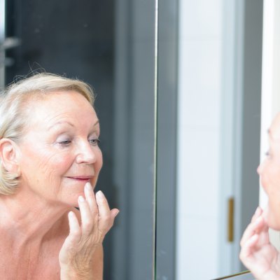 Senior lady checking her skin in the mirror