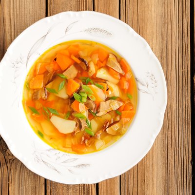 Porcini mushroom soup with potato and carrot in white plate