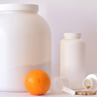 Big jar of protein powder, bottle of pills, orange