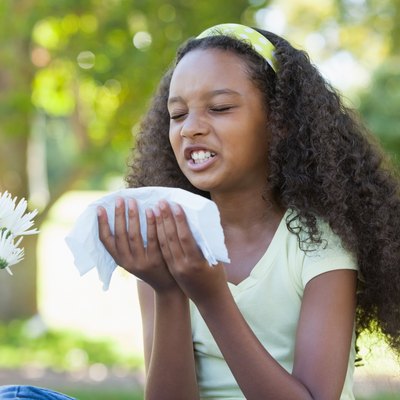 Young girl sitting by flower and sneezing in the park