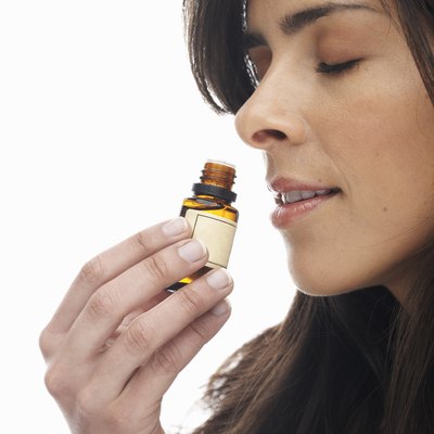 Young woman smelling aromatherapy oil, eyes closed