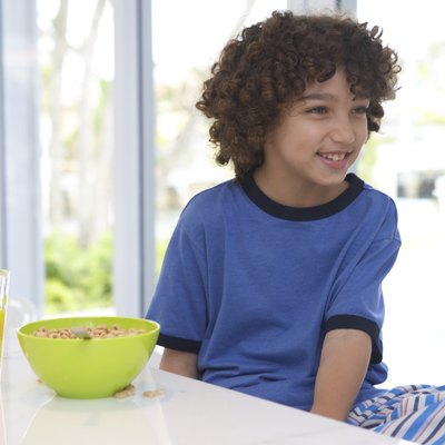 Boy (8-10) at breakfast table, smiling