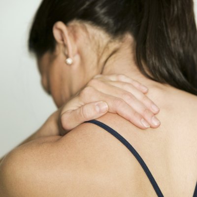 Woman massaging shoulder, in studio, rear view
