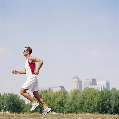 Man wearing sunglasses running in field, side view