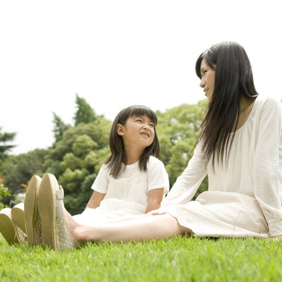 Mother and daughter sitting outside together on a lawn