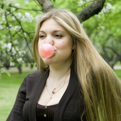 Playful blond girl blowing bubble with bubble gum