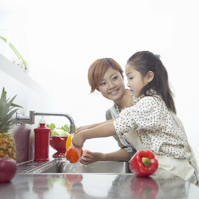 Mother and Daughter Washing Peppers at a Kitchen Sink