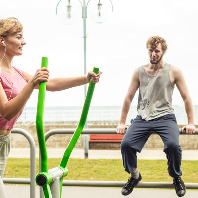 Man and woman exercising on elliptical trainer.