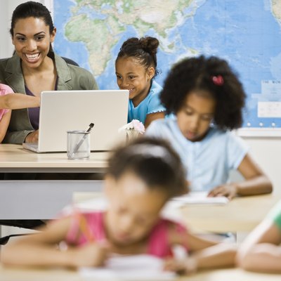 Mixed Race female teacher and students looking at laptop