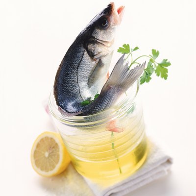 Raw fish, cooking oil, chervil, lemon and napkin on white background, close-up
