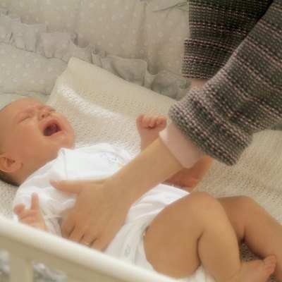 Mother reaching for crying baby in crib