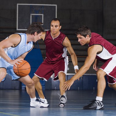 Man dribbling basketball against defenders