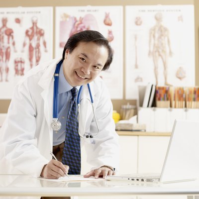 Asian male doctor writing at desk