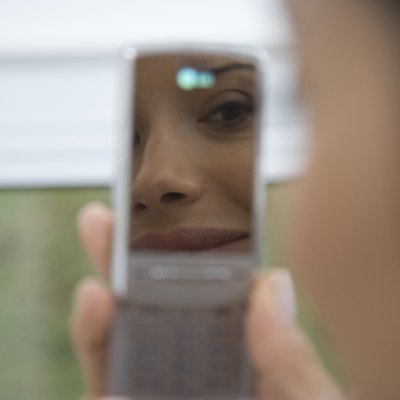 Reflection of young woman in mobile phone