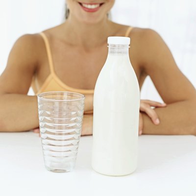 A woman sitting in front of a glass and a bottle of milk