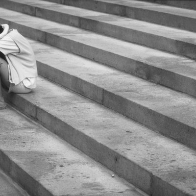 Girl sitting on steps with face down, outdoors (B&W)