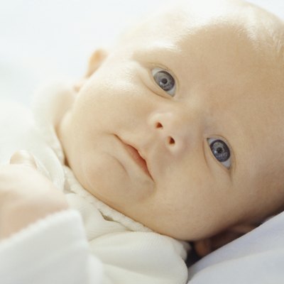 Baby (3-6 months) lying on white sheets, close-up