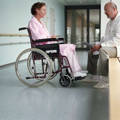 Mature male doctor talking to female patient in wheelchair