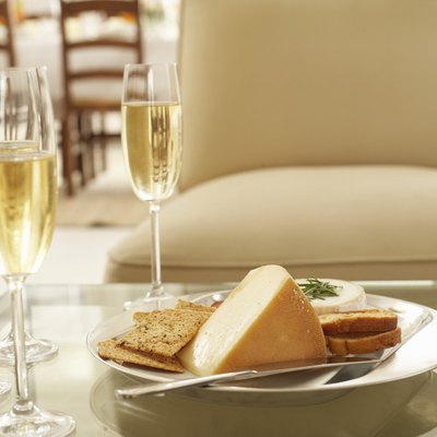 Glasses of wine by plate of cheese and biscuits on coffee table
