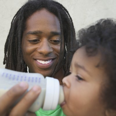 Mid adult man feeding a baby girl with a feeding bottle