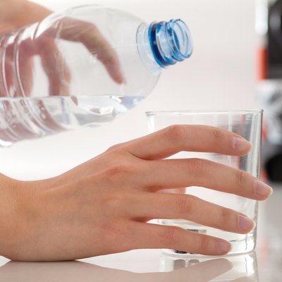 Female hands pouring bottled water into glass