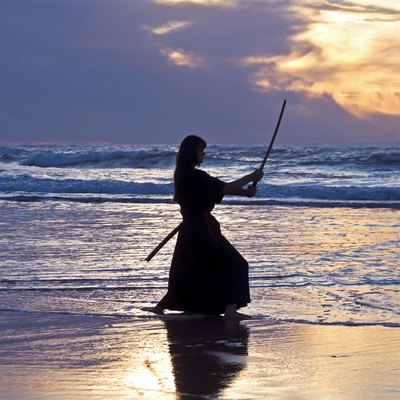 Young samurai women with Japanese sword(Katana) at sunset on the