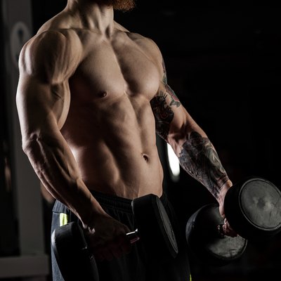 bodybuilder with dumbbells in a gym, exercising with a barbell